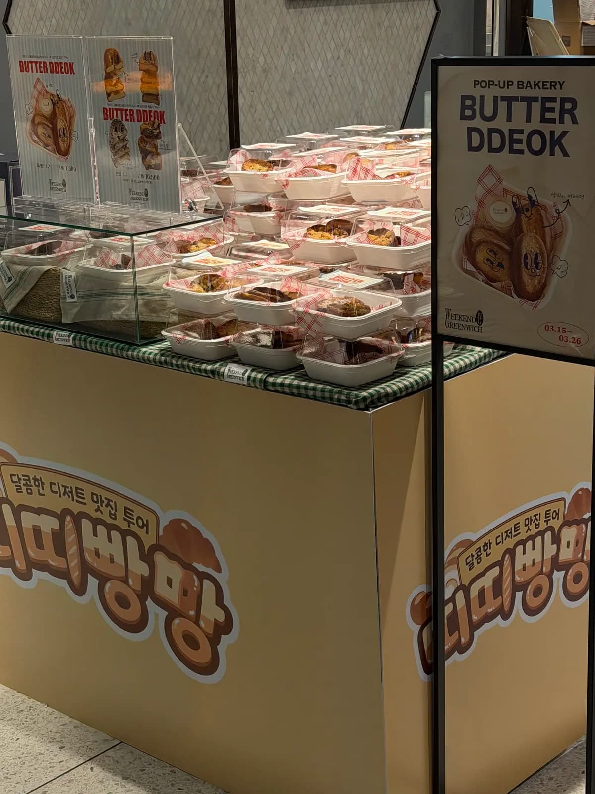 가격 안내판과 입간판 아래 포장된 버터떡이 쌓인 BUTTER DDEOK 팝업 매대